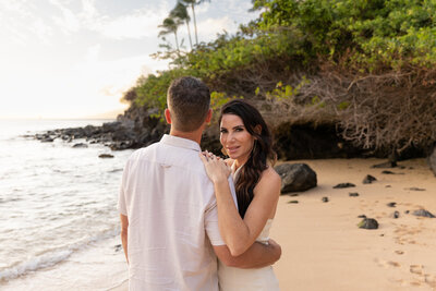 Maui Family Photographers capture woman hugging husband while smiling at camera during Maui family photos