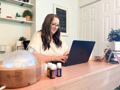 Ali from Deep Rooted Marketing working on black MacBook at her home office desk