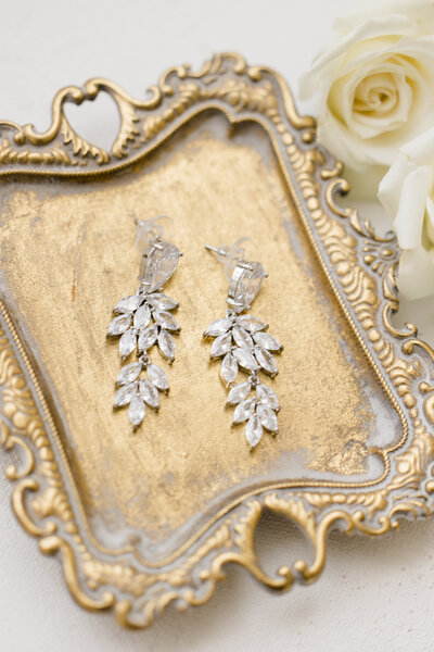 Diamond wedding earrings laying in a gold tray