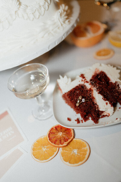 Wedding detail flat lay with red velvet cake, dried citrus, and champagne toast