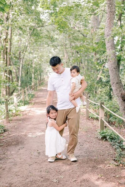 A father holds his son as his daughter clings to his leg during family photos.