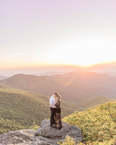 Couple kisses at the top of a mountain in the blue ridge mountains of north carolina