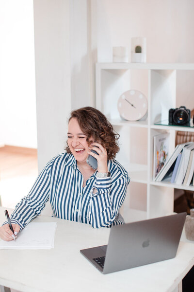Laura smiles while chatting on the phone with a client