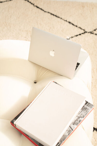 A white table with an open macbook pro and closed books