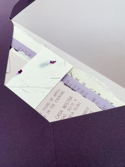 Wedding suite tucked into purple envelope