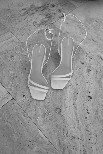 Minimal flatlay of Bride's heels and wedding bands. 