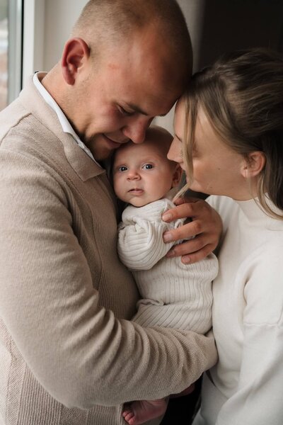 Een man en vrouw houden hun pasgeboren baby vast tijdens een newbornshoot door fotograaf Julia de Groot