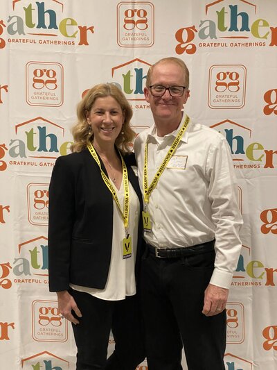 NexPhase Home Improvement business owners standing in front of a Grateful Gatherings event backdrop wearing volunteer badges.