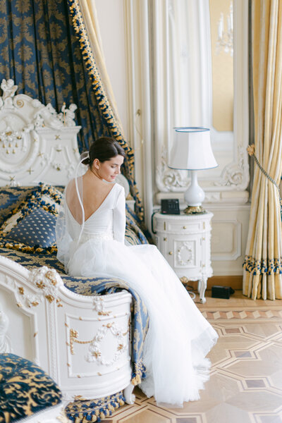 Elegant bride sitting at the edge of bed at the luxury Imperial suite in Vienna