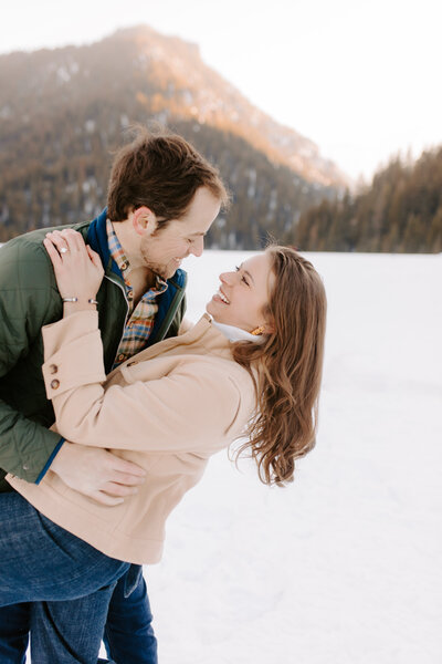 A man dips a woman down as they smile at each other in front of a mountain scape