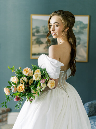 Elegant bride holding peach bouquet in romantic off-shoulder gown.