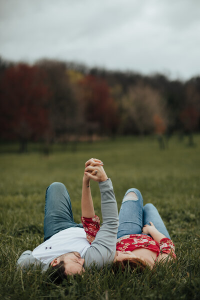 woman and man holding hands while laying in the grass