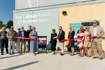 a corporate ribbon cutting ceremony showing the CEO cutting the red ribbon.  Captured outdoors at Kemptville District Hospital by Ottawa Event Photographer JEMMAN Photography Commercial