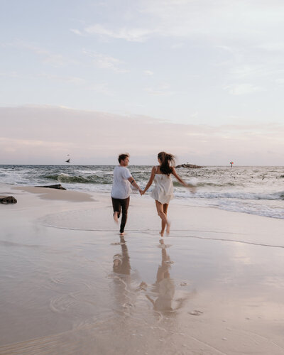 man and woman run along the beach