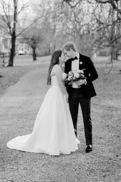 Black and white image of bride and groom gazing into each others eyes in autumn landscape