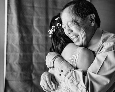 Wedding guest holds his daughter on his shoulder as she reaches down to cover his eyes