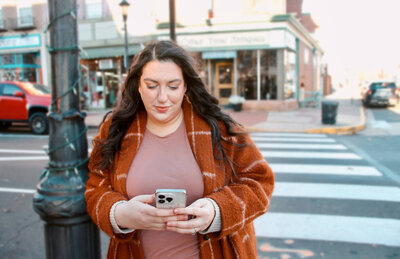 Photo of Sarah Weiss in an orange sweater looking at Tiktok and Instagram On Her Phone