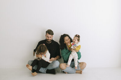 man & woman sitting on bed with kids