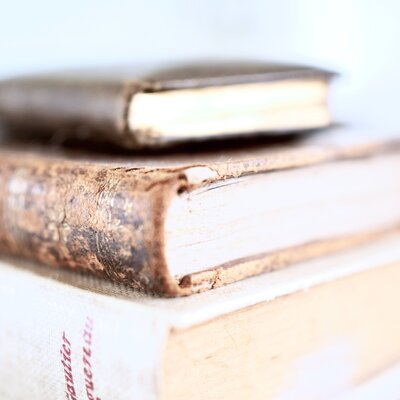 stack of worn, vintage looking books, leather and canvas covered