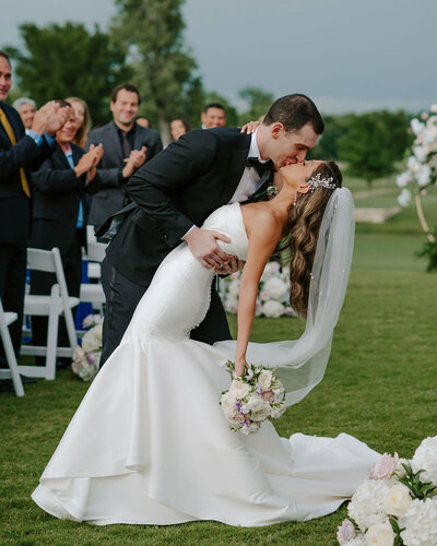 An elegant Dallas wedding ceremony at a lakeside club, with guests gathered around as the couple exchanges vows by the center aisle.