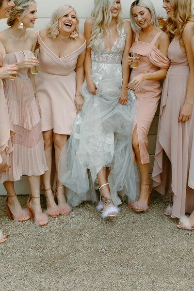 Bride laughing with her bridesmaids in fluffy fun shoes.
