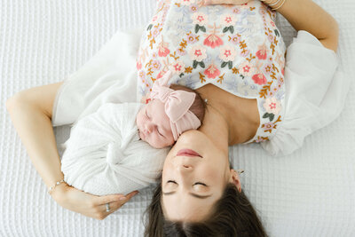 mom laying with newborn smiling with eyes closed