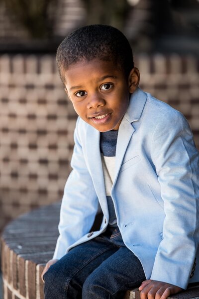 a boy in a blue suit jacket looks at the camera with a smile