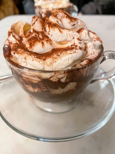 A Coffee with whipped cream and chocolate dessert presented in a glass coffee cup