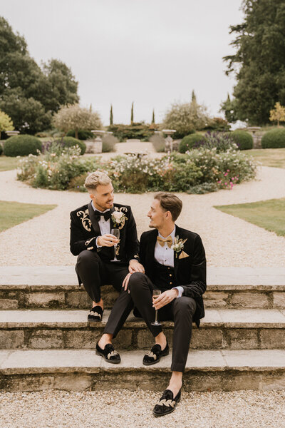 Grooms sitting on steps of came house gardens