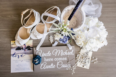 A photograph of wedding bridal details, including shoes, sign and flowers.