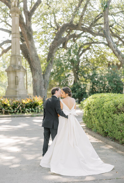 bride and groom kissing in a park