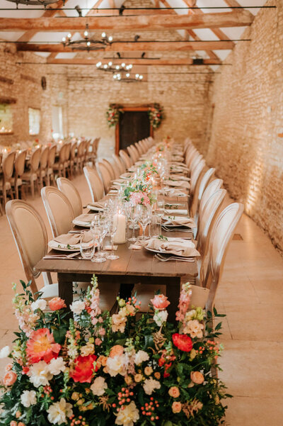 Wedding reception at Caswell House with long tables and bright, colourful floral arrangements