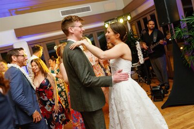 A newlywed couple laughing together as they dance 