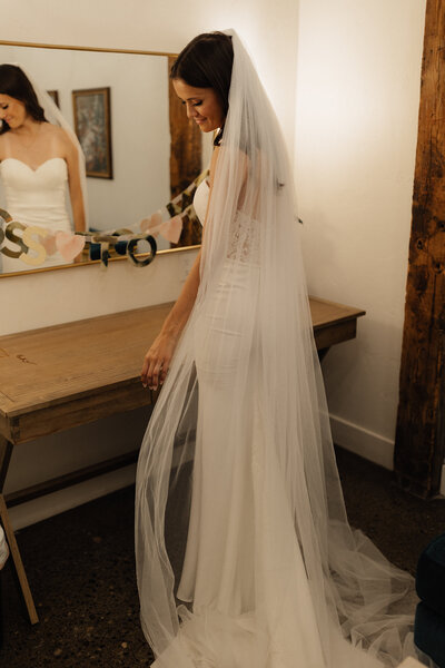 A bride in the getting ready room admiring her dress