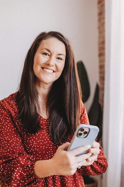 Kelli smiling in a striped shirt while holding a mug