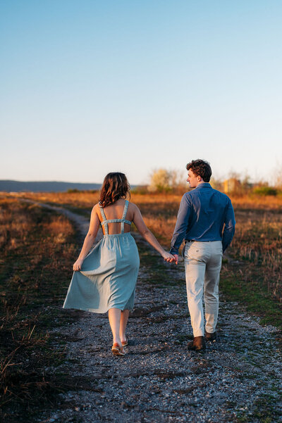 couple at engagement session walking away from camera at golden hour