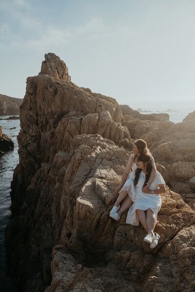 Bride wearing pink wedding dress and flowers in hair faces groom wearing green suit jacket looking into each other's eyes in Fern Canyon surrounded by light rays and trees taken by California elopement photographer Kasey Mantiply