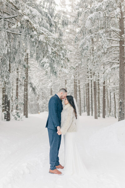Elegant bride in floral applique gown holds neutral-toned bouquet by soft natural window light | Zoe Evans Photography