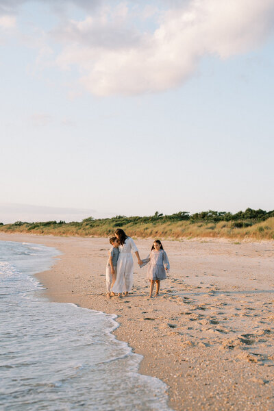 A family walking on the beach holding hands at sunset in Cape May, New Jersey