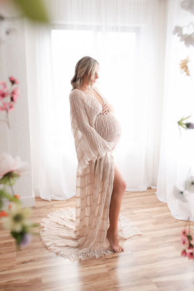 A pregnant mom in a reclamation dress in a gorgeous natural light studio.