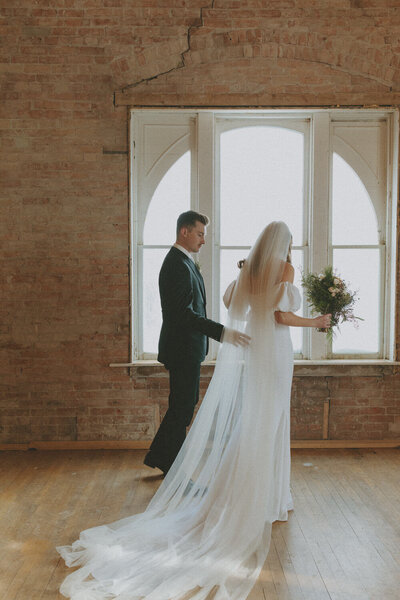 bride and groom walking to stand by window