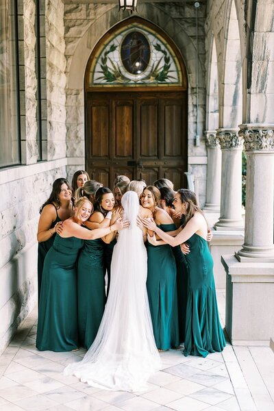 An asheville wedding photographer watches a bride embrace her bridesmaids during her wedding