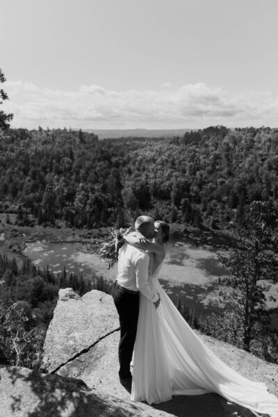 A newlywed couple kissing on a hiking trail 