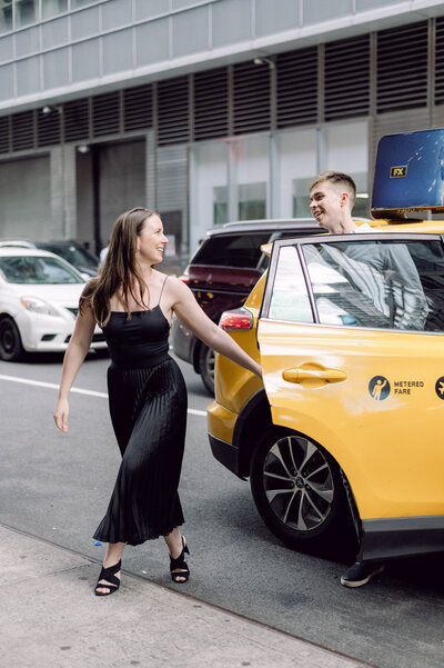 Engaged couple stepping out of a yellow NYC taxi during their New York City engagement session near Grand Central Station.