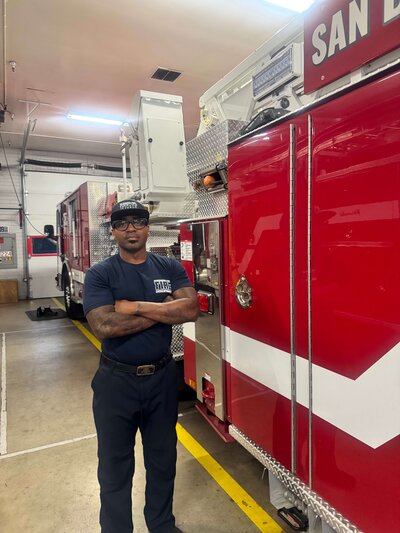 Firefighter standing next to the fire truck posed in Hurt Ink Next Level uniform t-shirt.