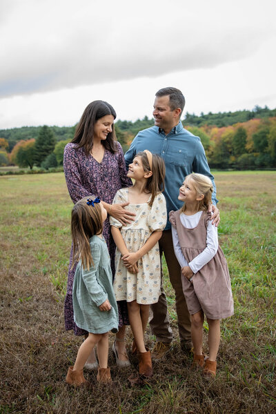 Family of five with three young daughters in dresses in  an open field