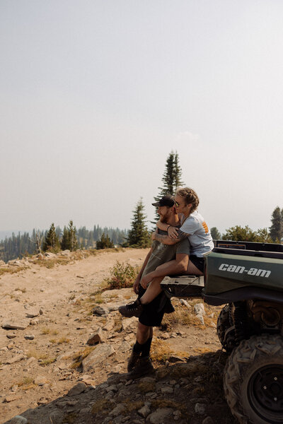 A person sitting on the back of a Can-Am and hugging their partner from behind