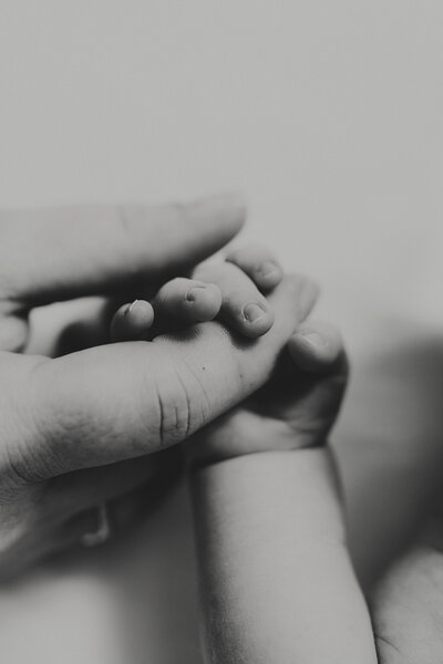 newborn fingers wrapped around moms hand