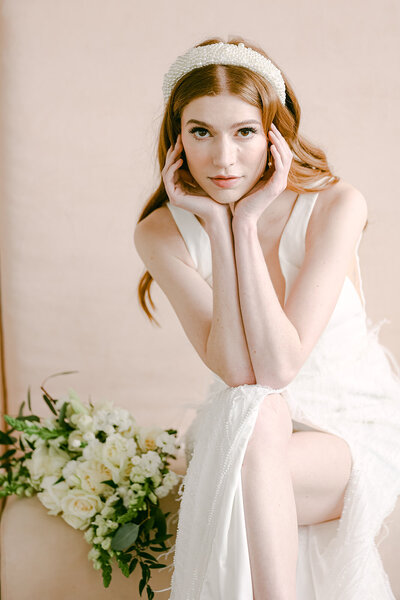 Beautiful woman with white elegant wedding dress posing for a photo in a pink couch