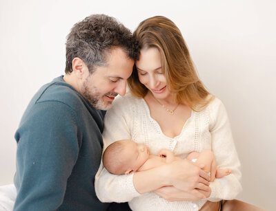 Pregnant mom wearing a white long dress with hands placed above and bellow belly.
